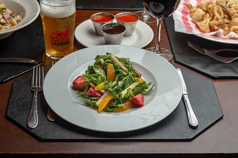 Arugula salad topped with orange slices and strawberrys